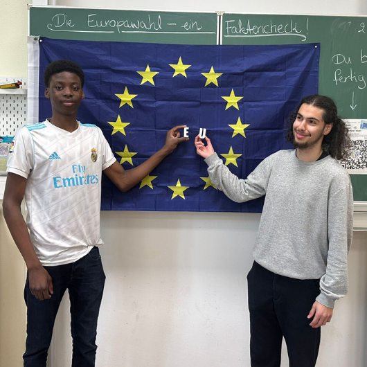 Zwei Schüler vor Tafel mit Europaflagge