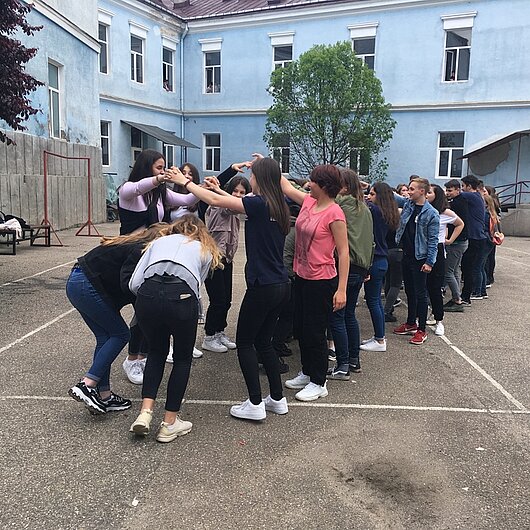 Schülerinnen und Schüler tanzen gemeinsam auf dem Pausenhof einer rumänischen Schule