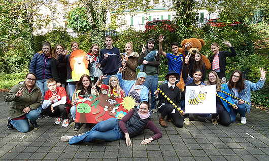 Eine gruppe von Schülerinnen und Schülern posiert für ein Gruppenfoto. Einige von ihnen halten Plüschtiere oder Plakate mit Bildern von Tieren in der Hand.