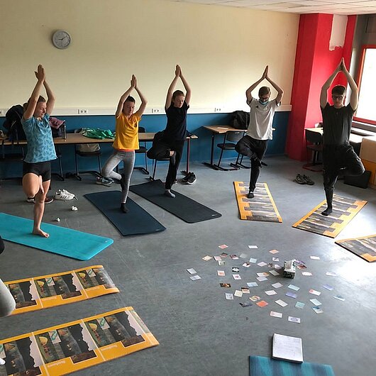 Gruppe von Schülerinnen und Schülern praktiziert Yoga
