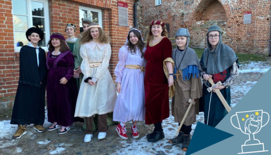Eine Gruppe von Schülerinnen und Schülern mit ihrer Lehrerin. Alle tragen mittelalterliche Kostüme.